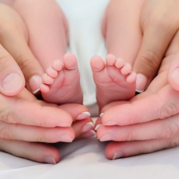 Close-up of white caucasian  parents  hands  holding small  newborn baby girl  feet. Concept of a happy family